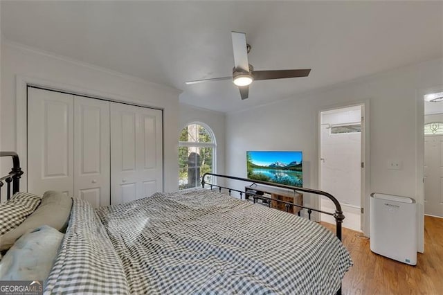 bedroom featuring light wood-type flooring, a closet, ornamental molding, and ceiling fan