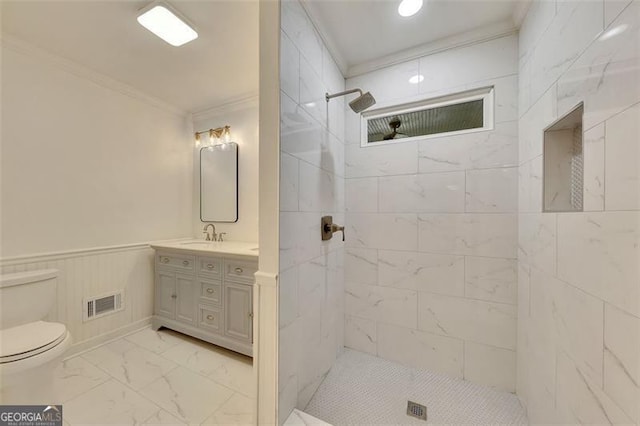 bathroom featuring tiled shower, wooden walls, toilet, vanity, and ornamental molding