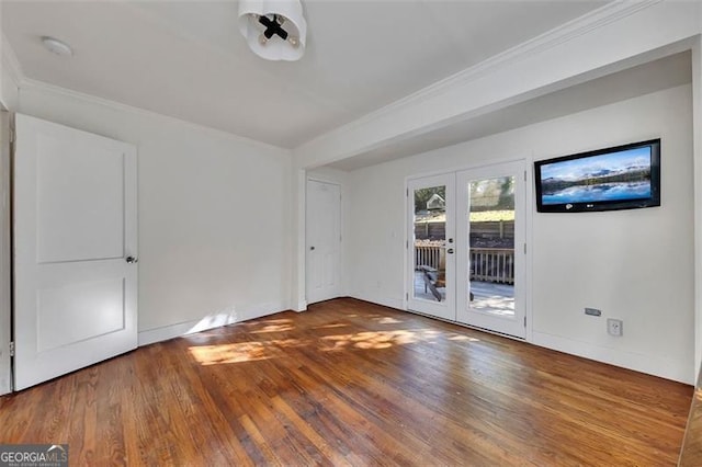 empty room with french doors, crown molding, and wood-type flooring