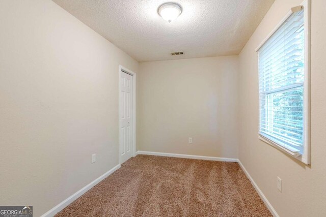 carpeted spare room with a textured ceiling