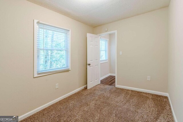 unfurnished room featuring dark colored carpet and a textured ceiling