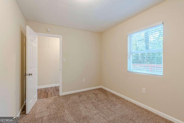 carpeted spare room with a textured ceiling