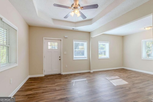 foyer featuring ceiling fan, wood-type flooring, a textured ceiling, and a tray ceiling