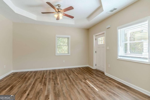 interior space with a healthy amount of sunlight, a raised ceiling, and wood-type flooring