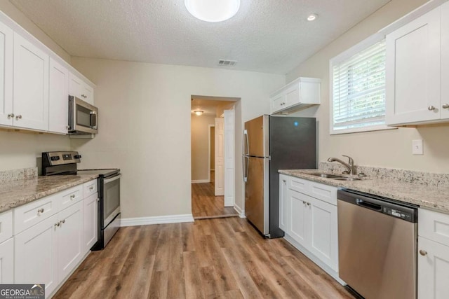 kitchen with white cabinets, a textured ceiling, stainless steel appliances, and sink