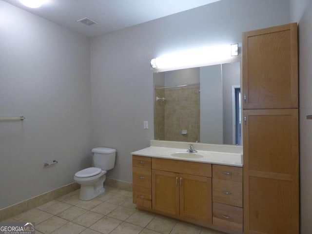 bathroom with tile patterned flooring, vanity, toilet, and tiled shower