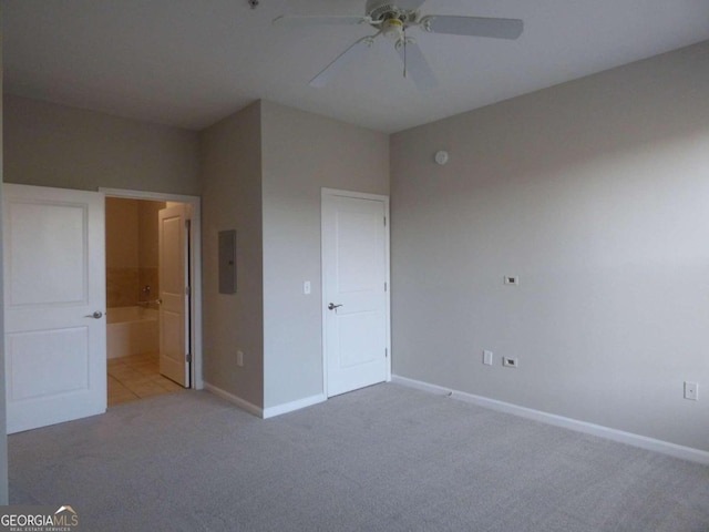 unfurnished bedroom with ceiling fan, ensuite bathroom, light carpet, and electric panel