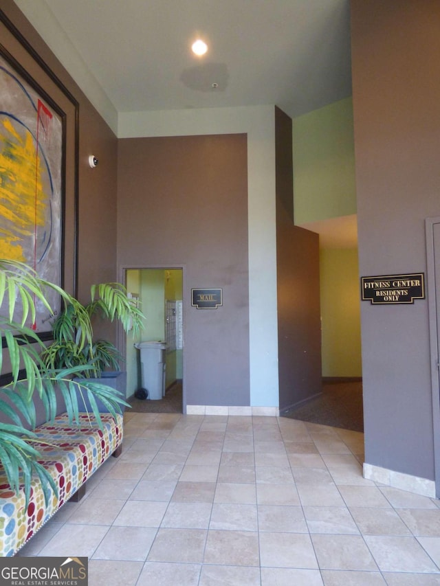 hallway with a towering ceiling and light tile patterned flooring