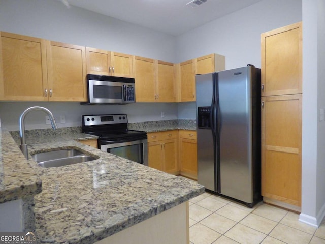 kitchen featuring sink, stainless steel appliances, light stone counters, light brown cabinetry, and light tile patterned flooring