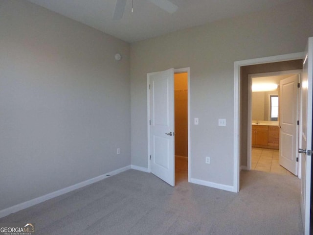 unfurnished bedroom featuring ceiling fan, a closet, light colored carpet, and a spacious closet