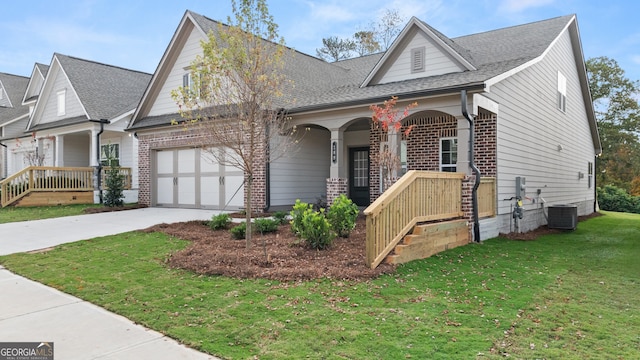 view of front of property with a front yard, a porch, a garage, and central air condition unit