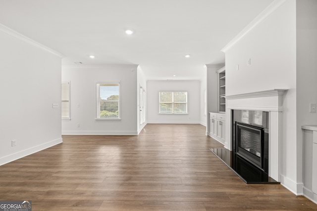 unfurnished living room with built in features, ornamental molding, dark wood-type flooring, and a high end fireplace