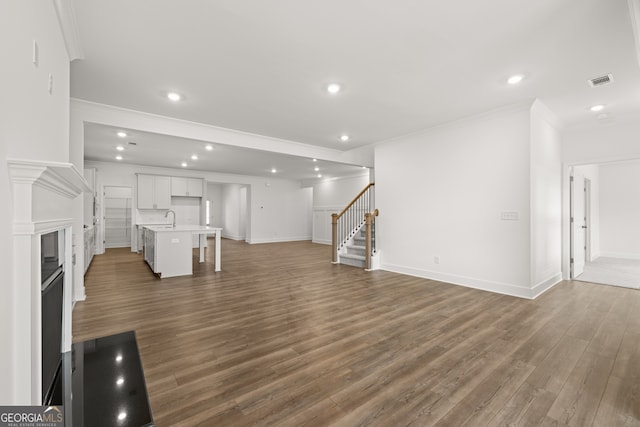 unfurnished living room featuring dark hardwood / wood-style flooring, ornamental molding, and sink