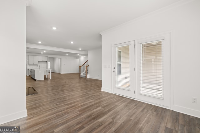 unfurnished living room with dark hardwood / wood-style floors, crown molding, and sink