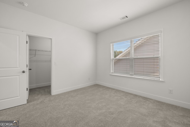 unfurnished bedroom with light colored carpet, a spacious closet, and a closet