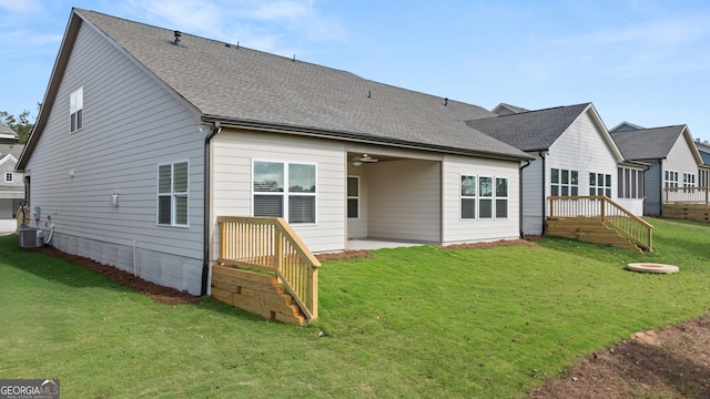 rear view of house featuring central air condition unit and a yard