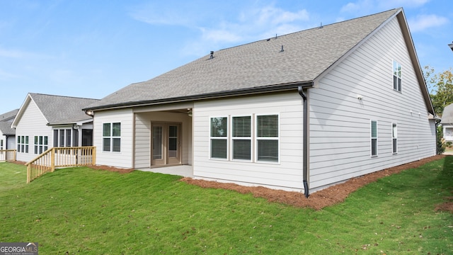 rear view of house featuring a wooden deck and a lawn