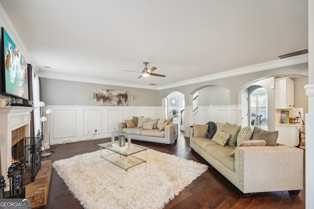 living room with a fireplace, ceiling fan, dark hardwood / wood-style flooring, and ornamental molding