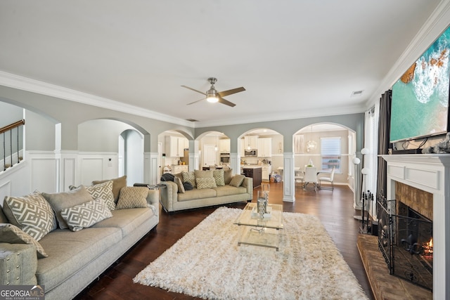 living room with a tile fireplace, dark hardwood / wood-style flooring, ceiling fan, and ornamental molding