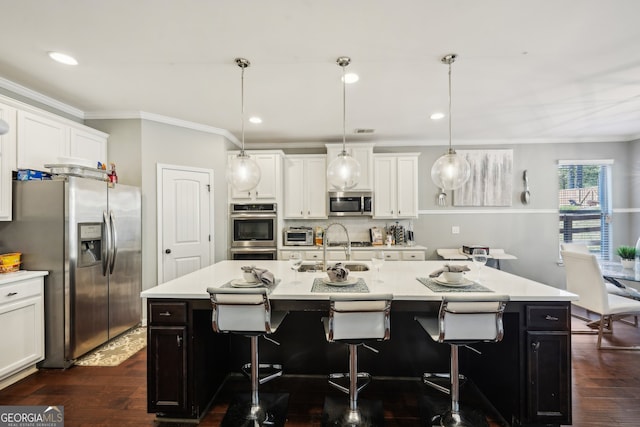 kitchen featuring a center island with sink, dark hardwood / wood-style floors, decorative light fixtures, and appliances with stainless steel finishes