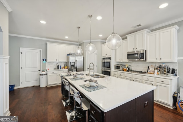 kitchen featuring white cabinetry, stainless steel appliances, dark hardwood / wood-style floors, an island with sink, and decorative light fixtures