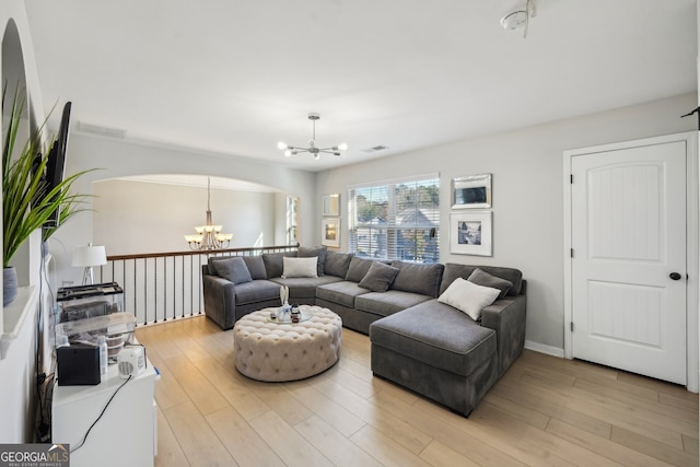 living room with light hardwood / wood-style floors and an inviting chandelier