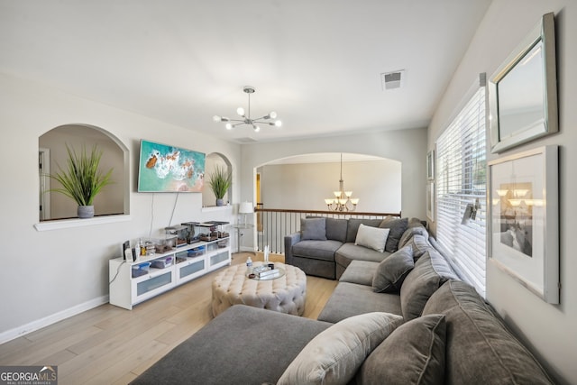 living room with light wood-type flooring and an inviting chandelier