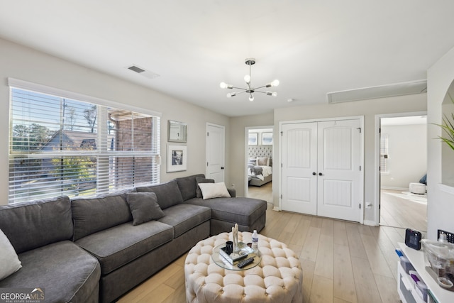 living room with light hardwood / wood-style floors and an inviting chandelier