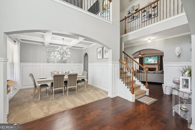 dining space with dark wood-type flooring, coffered ceiling, ceiling fan with notable chandelier, a towering ceiling, and beam ceiling