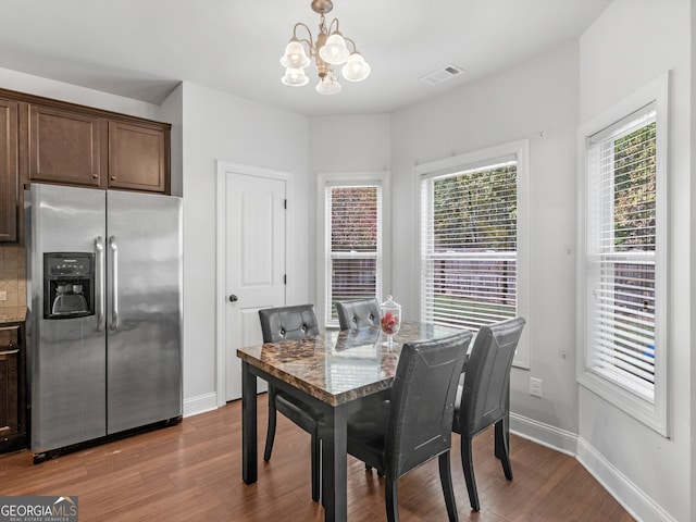 dining space with hardwood / wood-style flooring and an inviting chandelier