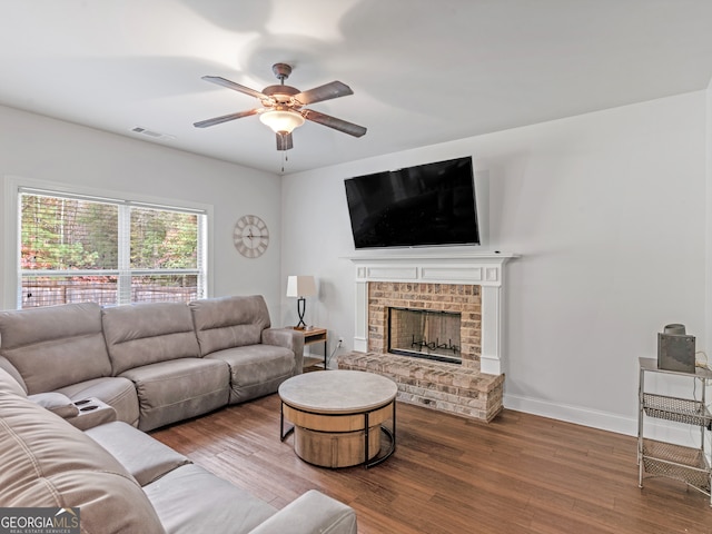 living room featuring a fireplace, wood-type flooring, and ceiling fan