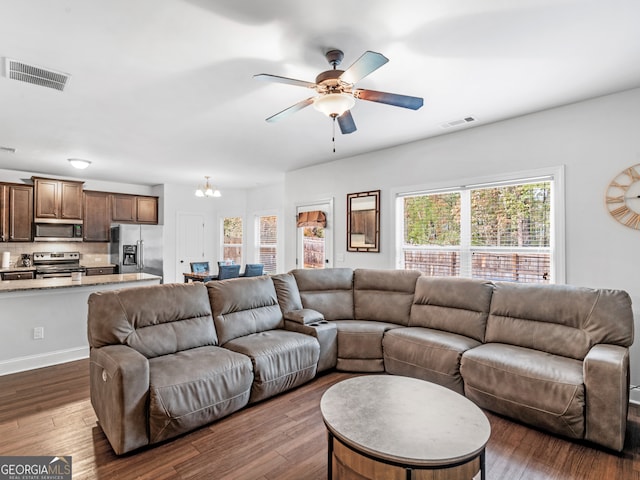 living room with ceiling fan with notable chandelier and dark wood-type flooring