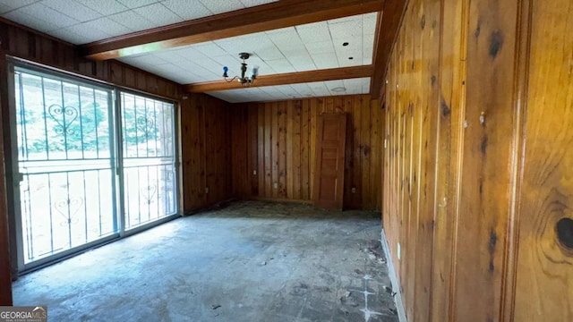 empty room with beam ceiling and wood walls