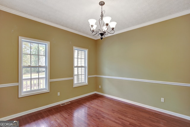 empty room with hardwood / wood-style floors, ornamental molding, a textured ceiling, and a chandelier