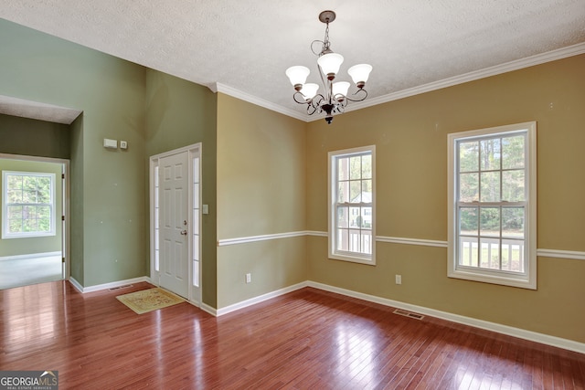 spare room with a wealth of natural light, hardwood / wood-style floors, a chandelier, and a textured ceiling