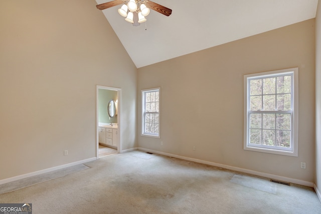 unfurnished bedroom with connected bathroom, ceiling fan, high vaulted ceiling, and multiple windows