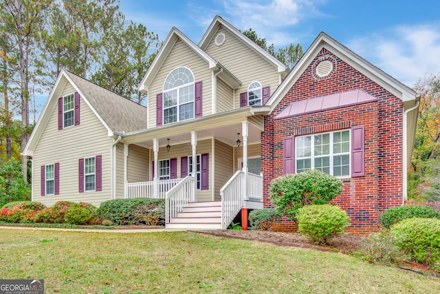 front facade with covered porch and a front yard