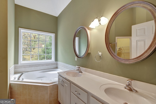 bathroom featuring tiled bath, vanity, and vaulted ceiling