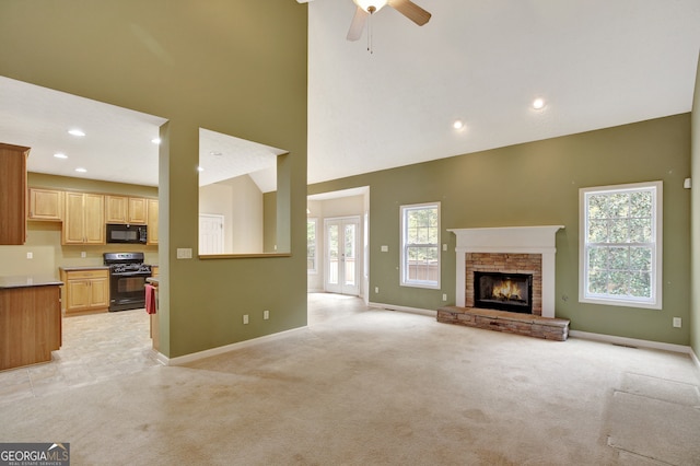 unfurnished living room featuring light carpet, a high ceiling, a fireplace, and ceiling fan