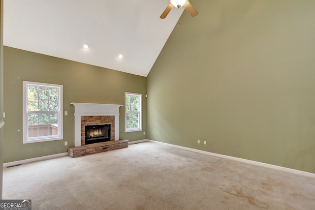 unfurnished living room featuring a fireplace, light colored carpet, high vaulted ceiling, and ceiling fan