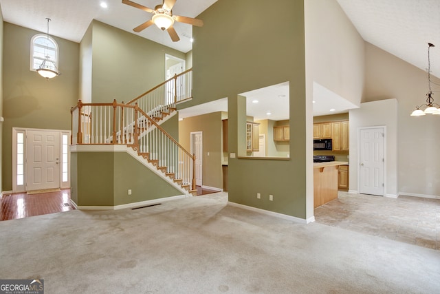 unfurnished living room with light carpet, high vaulted ceiling, and ceiling fan