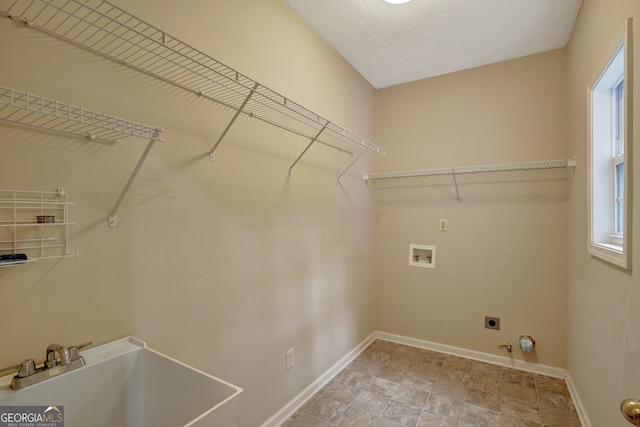 clothes washing area with sink, electric dryer hookup, hookup for a gas dryer, hookup for a washing machine, and a textured ceiling