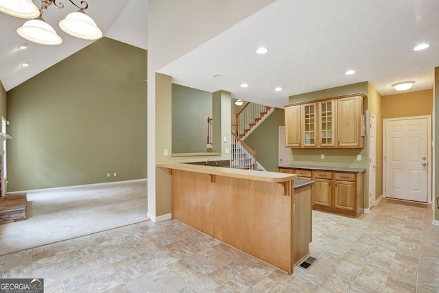 kitchen featuring kitchen peninsula, light colored carpet, pendant lighting, a breakfast bar area, and light brown cabinetry