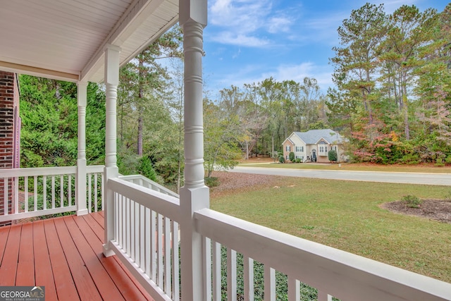 wooden terrace featuring a porch and a yard