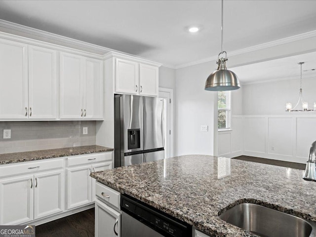 kitchen with sink, dark stone countertops, appliances with stainless steel finishes, decorative light fixtures, and white cabinetry