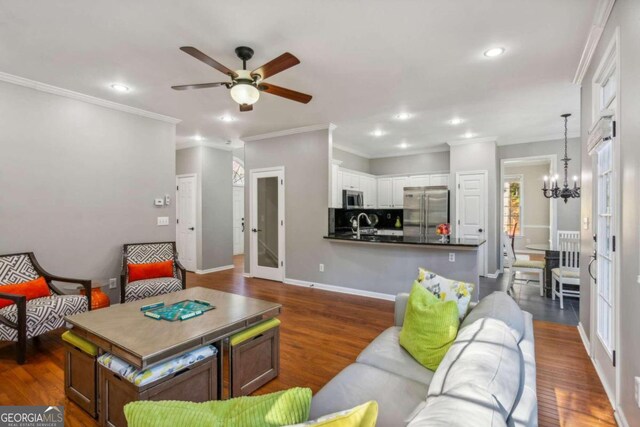 living room with dark hardwood / wood-style flooring, ceiling fan with notable chandelier, and ornamental molding