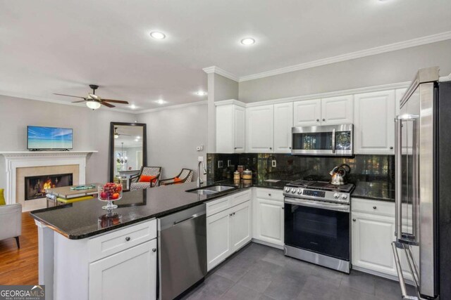 kitchen featuring white cabinetry, sink, stainless steel appliances, tasteful backsplash, and kitchen peninsula