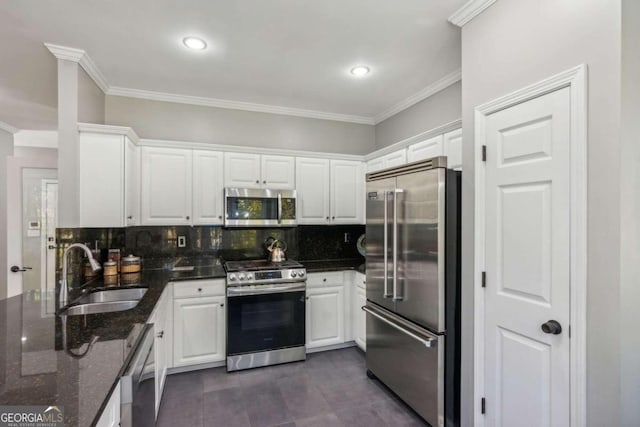 kitchen featuring ornamental molding, stainless steel appliances, sink, dark stone countertops, and white cabinets