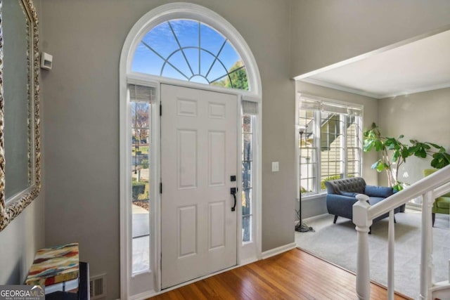 foyer with hardwood / wood-style flooring, crown molding, and a healthy amount of sunlight