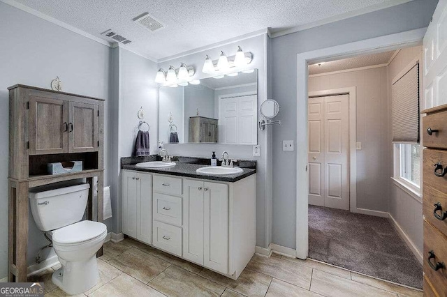 bathroom with tile patterned floors, vanity, a textured ceiling, crown molding, and toilet